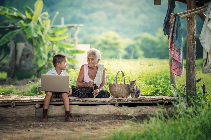Großmutter und Kind sitzen mit Laptop im Freien